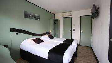 Habitación de hotel con dos camas, una televisión de pantalla plana, un cuadro en la pared y un espejo.