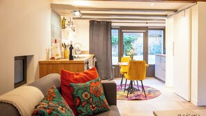 Een moderne woonkamer met een bank, een eethoek met tafel en stoelen, en een keuken met een aanrecht en apparatuur.