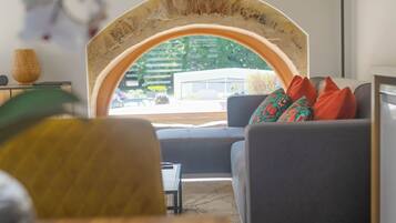 Un salon avec un canapé, une table en bois et une vue à travers une fenêtre en arc de cercle.