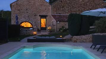 Een gebouw van steen met een zwembad ervoor.