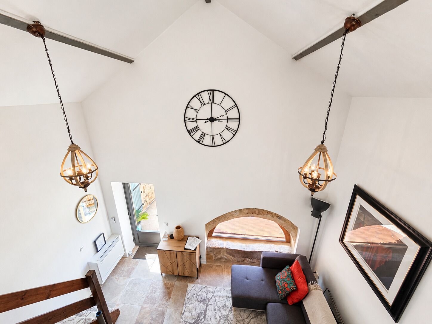 Ein geräumiger Raum mit einer großen Wanduhr, einer hölzernen Bank und einem Sofa mit Kissen.