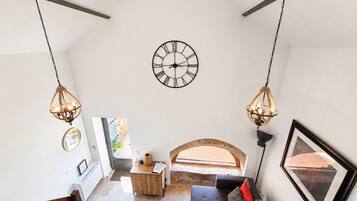 Ein geräumiger Raum mit einer großen Wanduhr, einer hölzernen Bank und einem Sofa mit Kissen.