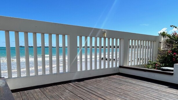 A wooden deck with a white railing overlooking a beach. - Best Beach Location in Isla Verde, Beach Front Building! (Carolina)