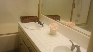 Un bagno con due lavandini, uno specchio e una doccia. Ci sono cesti di vimini sul ripiano.