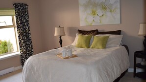 Un letto rifatto con cura, un vassoio con tazze bianche, un’opera d’arte floreale alle pareti e una finestra con tende a motivi.