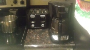 Una cucina con forno a microonde, tostapane e macchina del caffè sul piano di lavoro.