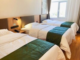 Habitación de hotel con dos camas, una mesita de noche con teléfono y una ventana con cortinas.