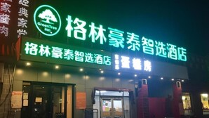 A hotel entrance with a neon sign, glass doors, and a wet ground. - Greentree Inn Beijing Fangshan District Doudian Road Jinxin Yuan Express Hotel (Fangshan)