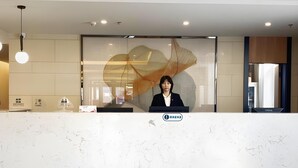 A reception desk with a modern design, featuring a marble countertop and a large, abstract artwork on the wall behind. - Greentree Inn Beijing Fangshan District Doudian Road Jinxin Yuan Express Hotel (Fangshan)