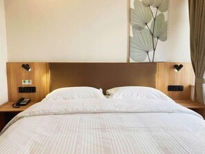 A hotel room with a large bed, two bedside tables, a phone, and a wall-mounted light fixture. - Greentree Inn Beijing Fangshan District Doudian Road Jinxin Yuan Express Hotel (Fangshan)