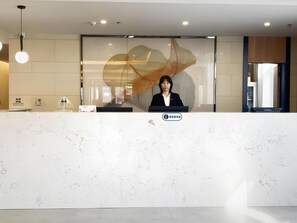 Una reception dal design moderno, con un logo e una segnaletica che indica un albergo o struttura simile.