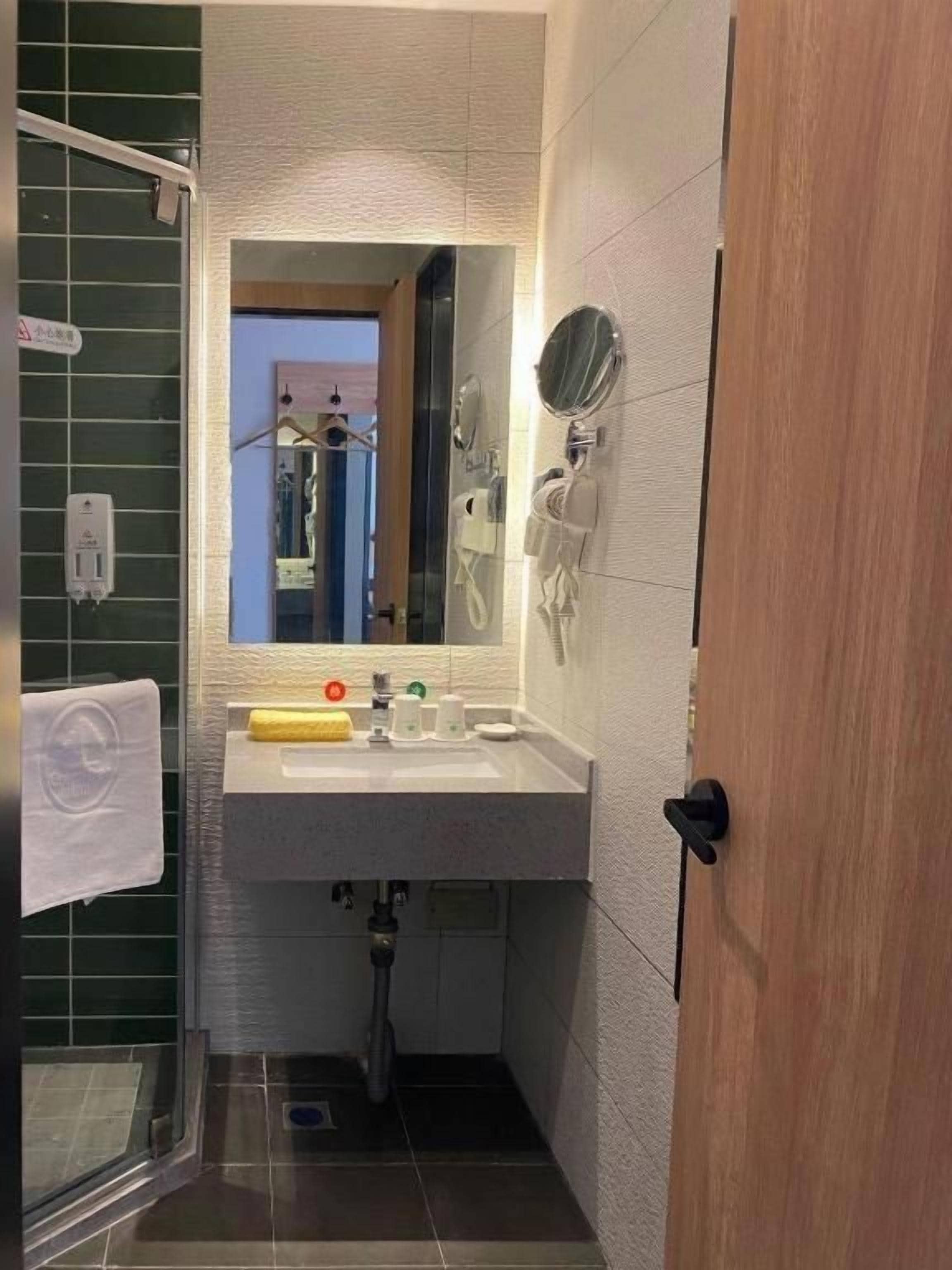 Une salle de bain équipée d’un lavabo, d’un miroir, d’un porte-serviettes et d’un espace douche.