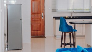 Une cuisine avec une porte en bois, un réfrigérateur, un évier et une chaise bleue.