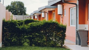Une rangée de bâtiments modernes aux toits orange, avec une haie bien entretenue au premier plan.