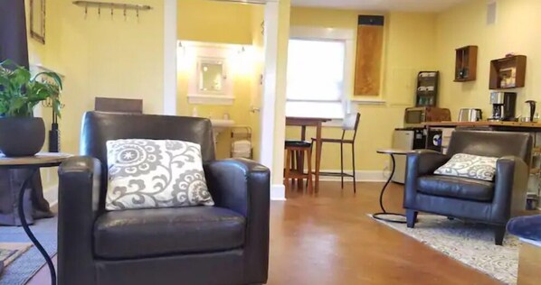 Un salon comprenant deux fauteuils en cuir, une table basse et un coin repas avec une table et des chaises.