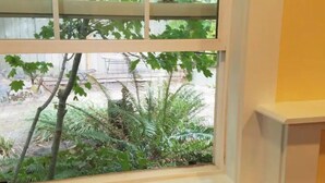 A window with a view of a garden with trees and shrubs. - Charming, Private, Detached Studio! (Portland)