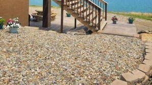 A wooden cabin with a wooden staircase leading to a deck overlooking a lake.