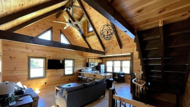 A spacious cabin with a loft bedroom, a kitchen, and a living area with a large sofa.