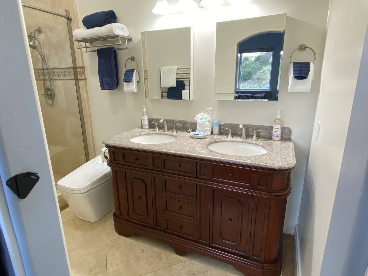 Un bagno con due lavabi, una doccia e un water. Asciugamani e articoli da toilette sono presenti sul mobile.
