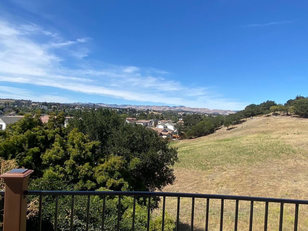 A residential area with houses and a grassy hill.