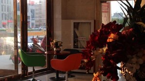 A modern interior with a large window, a green chair, a red chair, and a vase with flowers. - Greentree Inn Bengbu Huaiyuan County Yudu Avenue Xinhe Road Express Hotel (Bengbu)