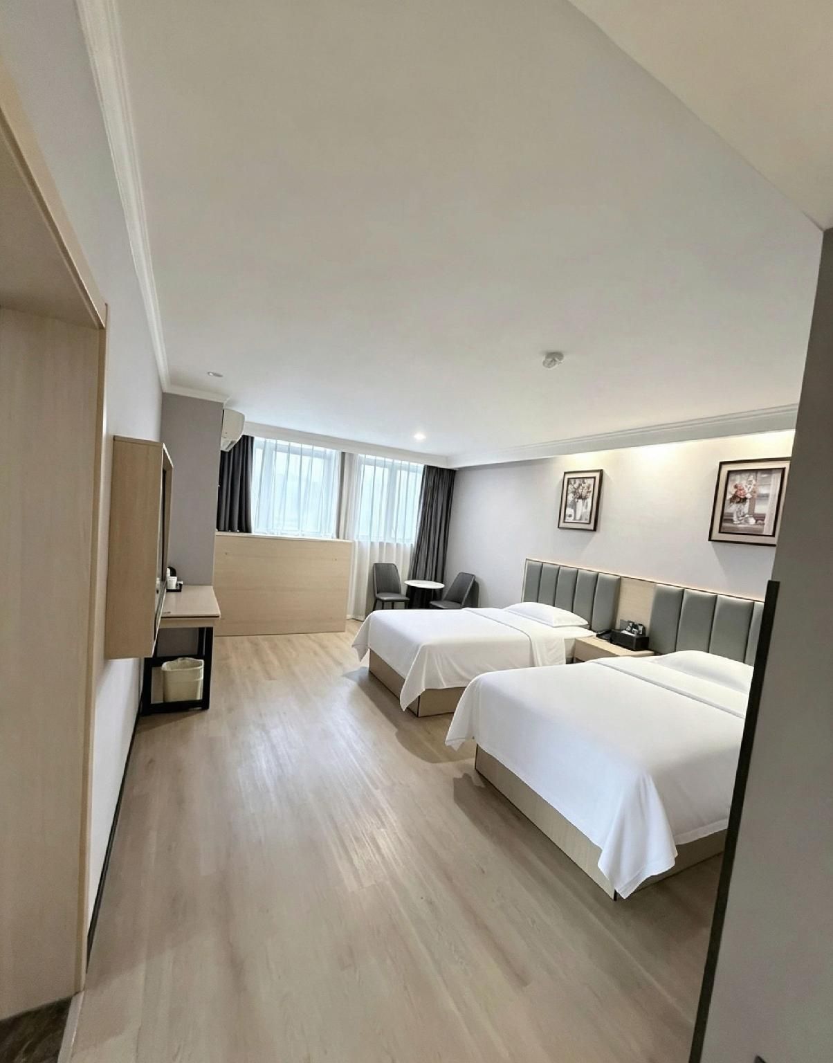 A hotel room with two beds, a desk, and a chair.