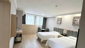 A hotel room with two beds, a desk, and a chair.