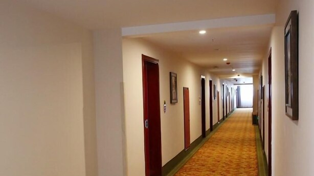 A hotel corridor with a carpeted floor, doors on the left, and framed pictures on the right. - Greentree Inn Bengbu Huaiyuan County Yudu Avenue Xinhe Road Express Hotel (Bengbu)