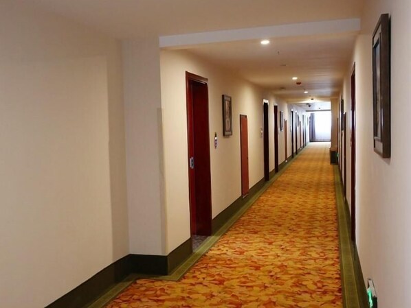 A hotel corridor with a carpeted floor, doors on the left, and framed pictures on the right. - Greentree Inn Bengbu Huaiyuan County Yudu Avenue Xinhe Road Express Hotel (Bengbu)