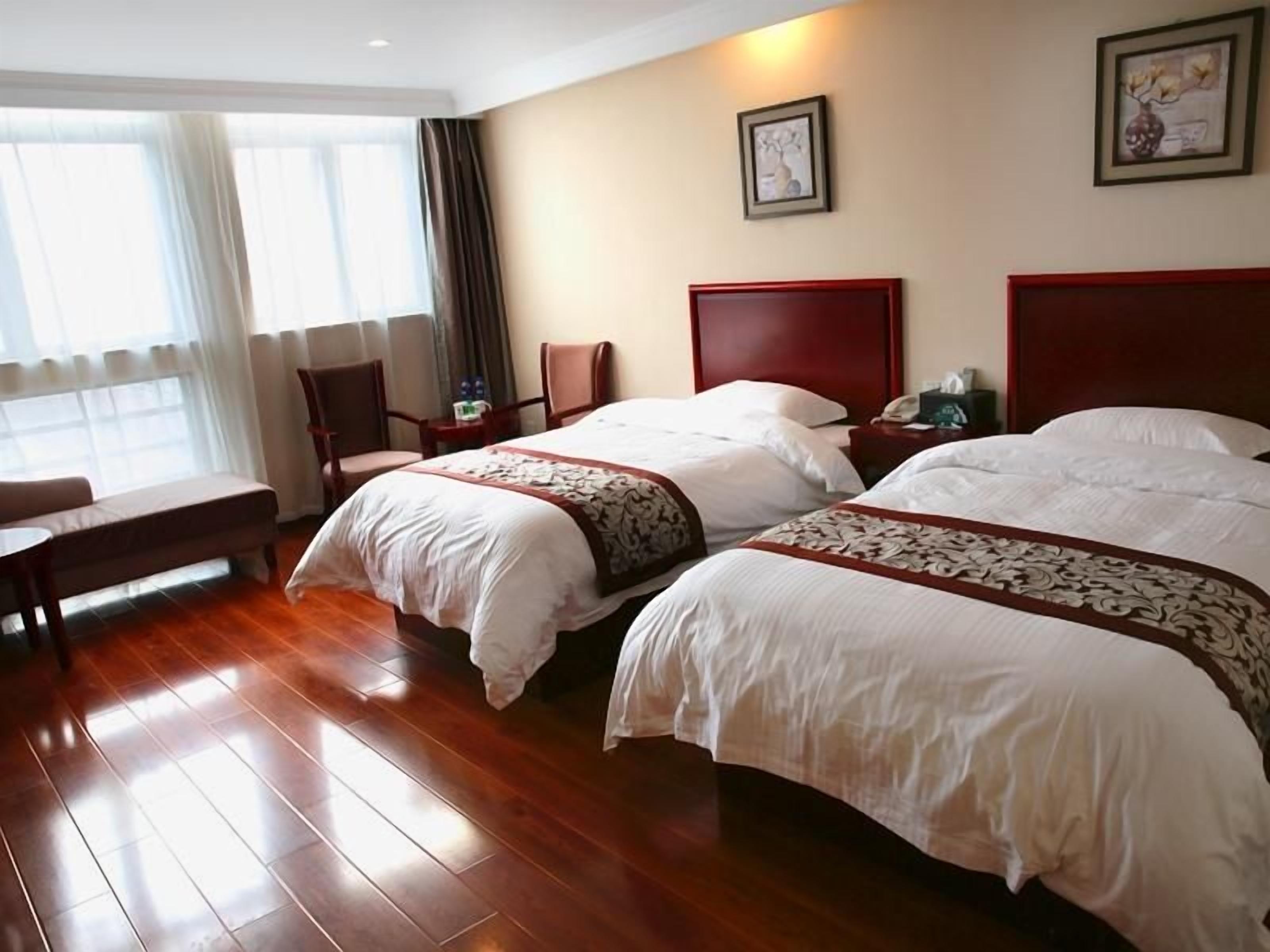 A hotel room with two beds, a desk, and a chair.