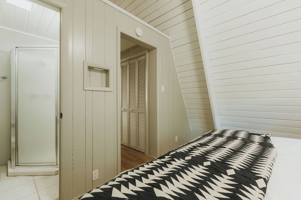 Ein Schlafzimmer mit einem Bett, einem Kleiderschrank und einer Tür zu einem Flur.