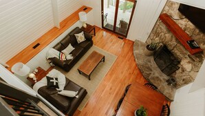Un salon spacieux avec un canapé en cuir marron, une table basse en bois et une cheminée en pierre.