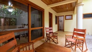 Un interno in legno con zona pranzo, poltrone a dondolo e un'ampia finestra che si affaccia su un giardino.