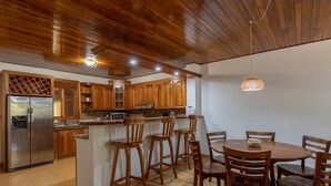 Eine Küche mit Holzausstattung, einem Edelstahlkühlschrank und einem Essbereich mit Holztischen und -stühlen.