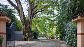 A gated entrance to a property with a paved driveway leading to a covered area.