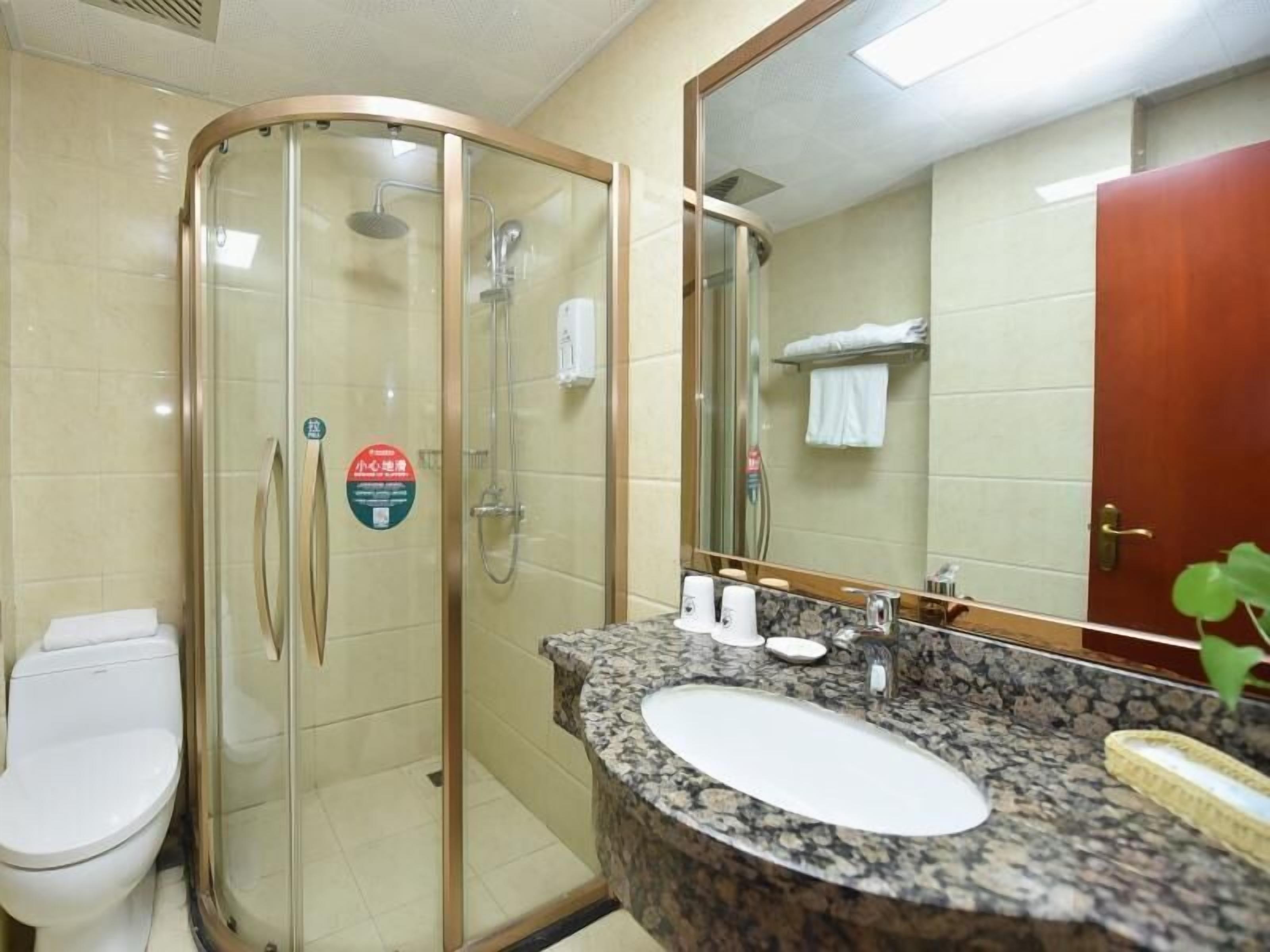 Casa de banho com chuveiro envidraçado, lavatório com bancada de granito e espelho sobre o lavatório.