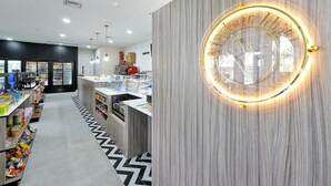 Un hall d'hôtel moderne avec un panneau circulaire illuminé, un comptoir d'accueil et un distributeur automatique.