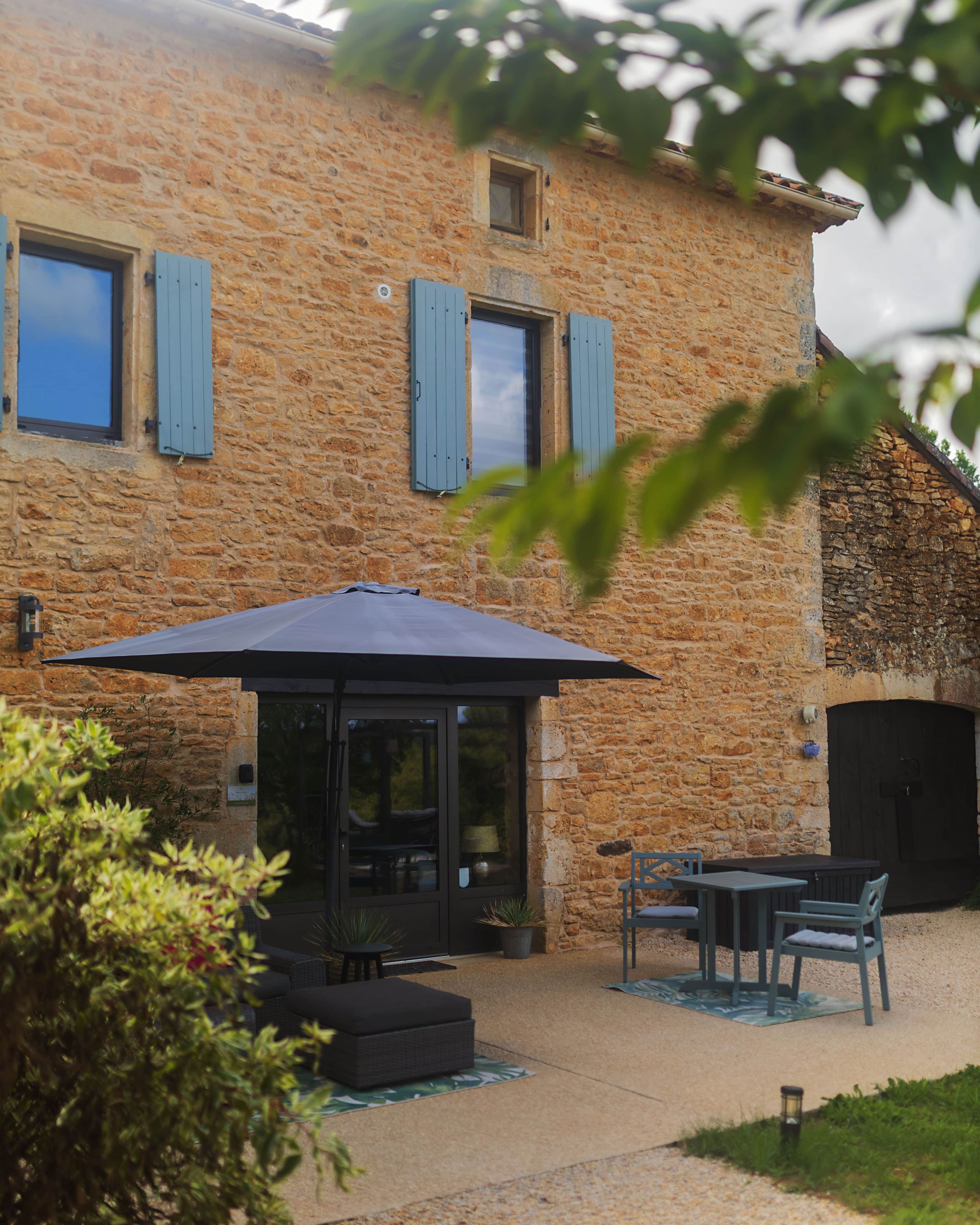 Un edificio in pietra con patio coperto, posti a sedere all'aperto e un'uscita che dà su un ambiente interno.