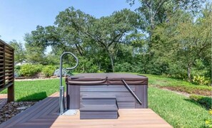 Relax in a serene garden setting, surrounded by lush greenery, with a hot tub and deck offering a peaceful retreat.