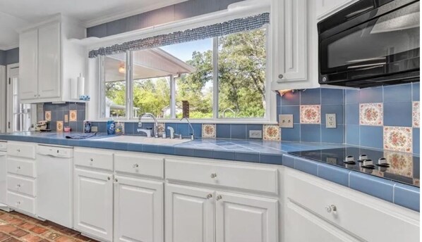 Enjoy a spacious kitchen with a large window offering a view of the outdoors and decorative tile backsplash.