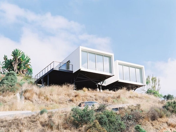 A modern house with a flat roof, large windows, and a balcony.