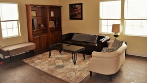 A living room with a sofa, coffee table, bench, and a wooden bookshelf. - The Gateway: experience a stylish and welcoming lodging, perfect for groups. (Grand Forks)