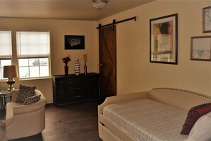 Une chambre à coucher avec un lit, une commode, une chaise et une fenêtre.
