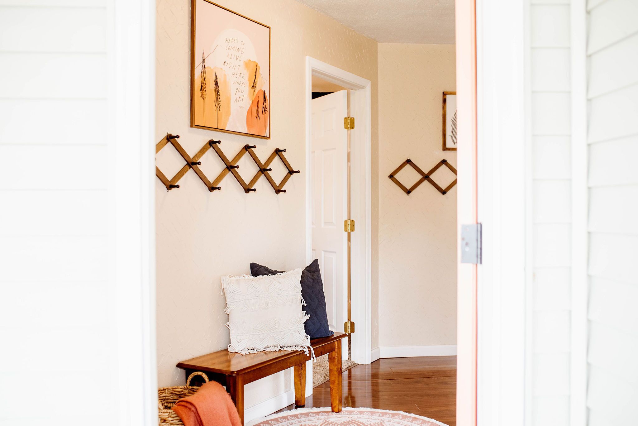 A hallway with a wooden bench, a rug, and wall-mounted decorations.