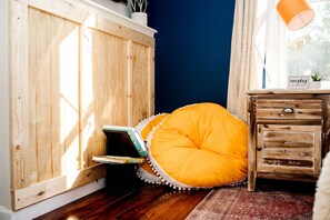 Een kamer met een houten kast, een tafeltje met een lamp en een kussen.