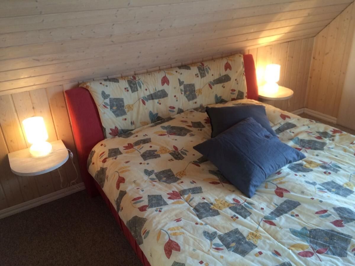 Un dormitorio con cama, dos lámparas de noche y techo de madera.