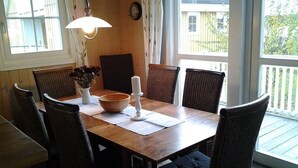 Una mesa de madera con seis sillas de mimbre, una vela blanca y un cuenco sobre un suelo de madera.