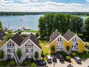 A row of two-story buildings with balconies, a parking area, and a lake view. - App. „Kapitän“ 109m ², 8 Pers. im Marinapark Scharmützelsee, Sauna, Whirlpool, Kamin (Wendisch Rietz Siedlung)