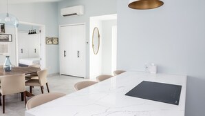 A modern kitchen with a marble island, pendant lights, and a dining area with chairs. - The Ampersand Sky Villa: Iconic, Artful Luxury (Charlotte Amalie, Saint Thomas)