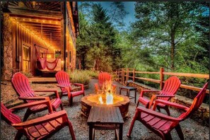 A wooden deck with red chairs and a fire pit. - Mystic Creek Retreat (next to Blue Ridge) (Mineral Bluff)